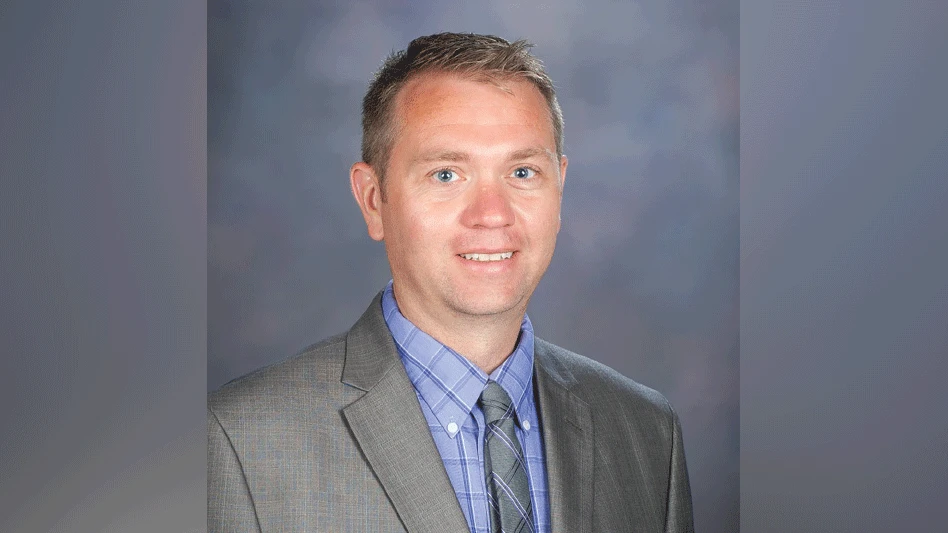 A headshot of a man wearing a blue shirt and gray suit with a tie.