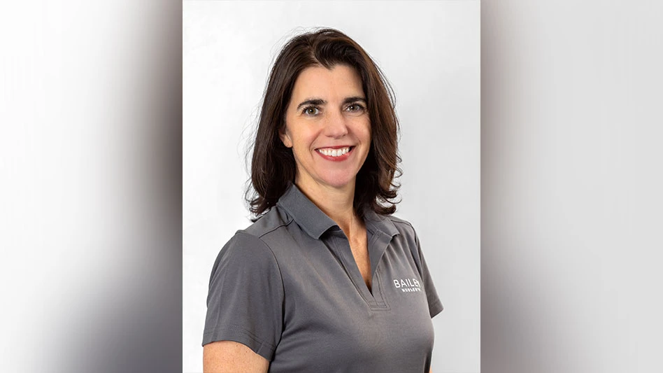 A headshot photo of a smiling woman with brown hair wearing a gray polo shirt.
