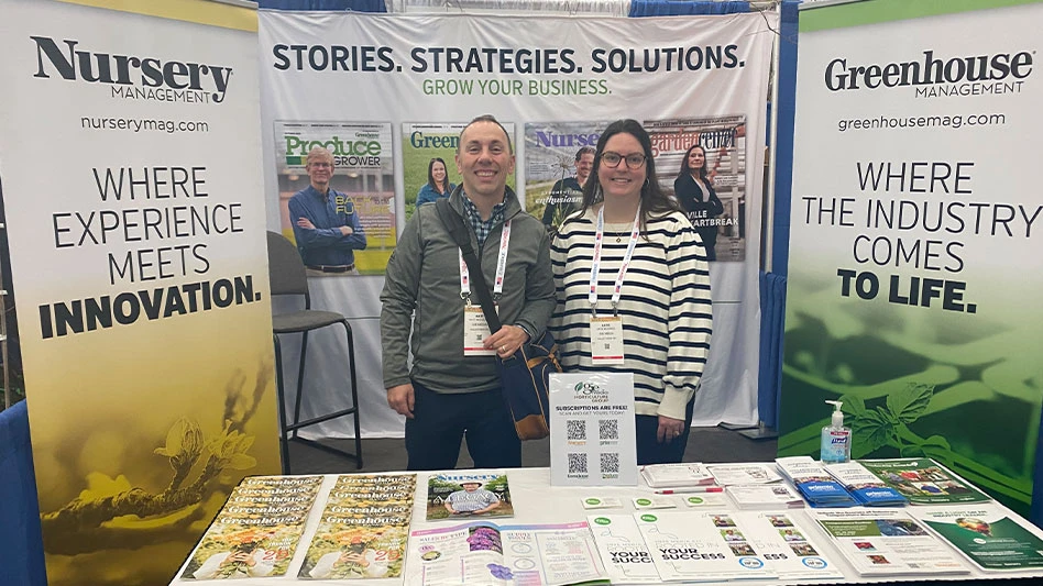 Two people stand in a trade show booth.