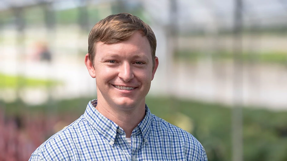 Man poses for picture in greenhouse.