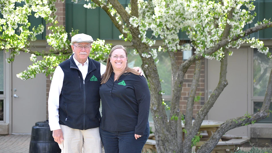 A smiling man and woman pose for a photo in front of a tree.