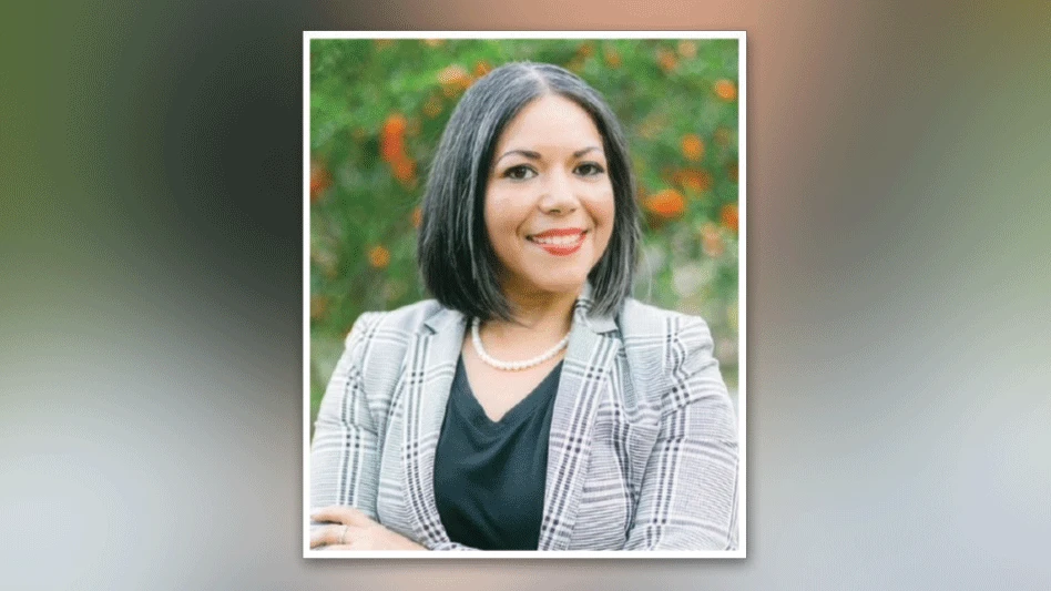 Woman smiling for headshot in front of flower field.