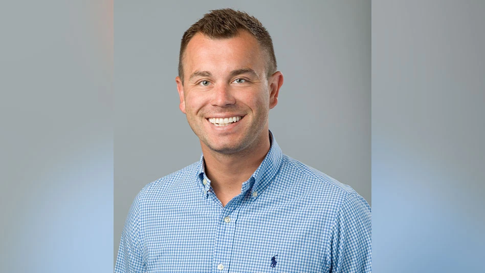 A headshot photo of a smiling man wearing a blue polo dress shirt.