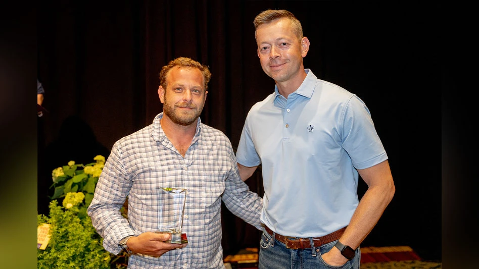 A man is presented with an award by another man.