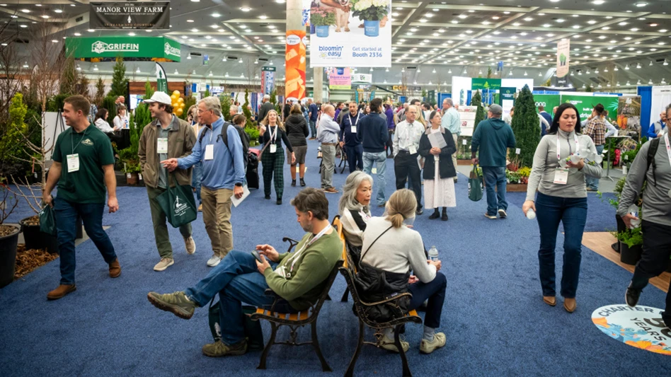 A convention center with three people seated on benches and dozens of people walking around them.