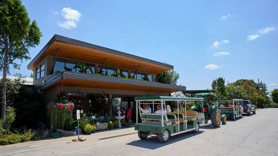 The entrance of a building with a two-tier roof and a tractor bus with people.